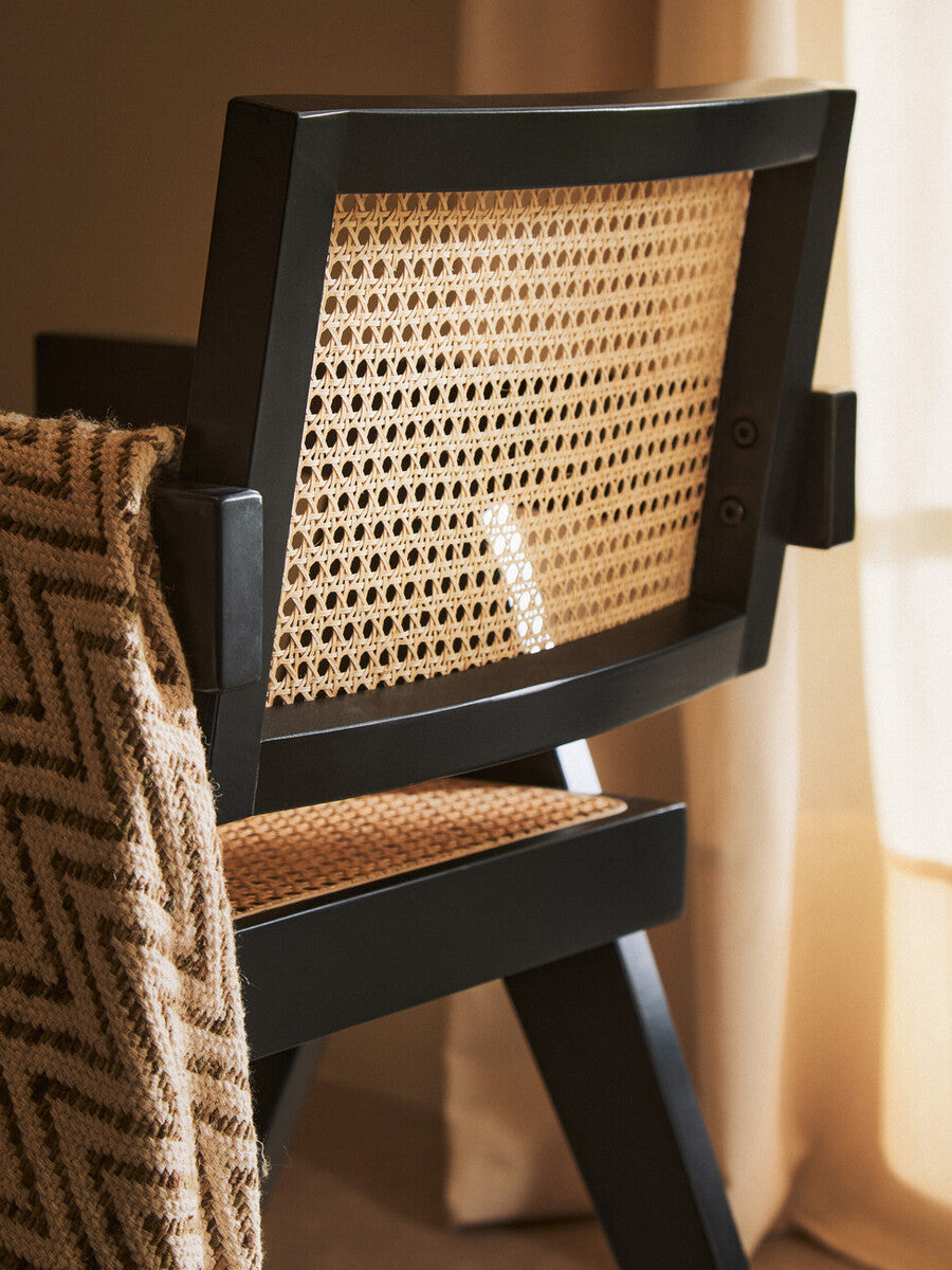 Chair with black frame and woven backrest in a room setting