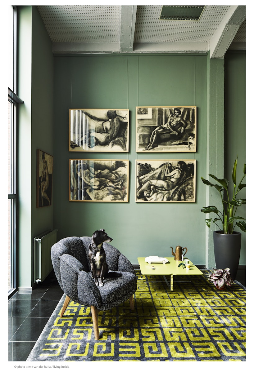 "Living room with green walls, gray armchair, yellow coffee table, and decorative elements."