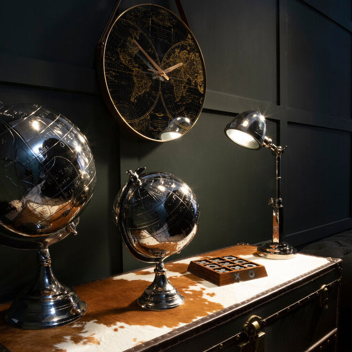 "Decorative table with globes, lamp, and map against a dark wall."