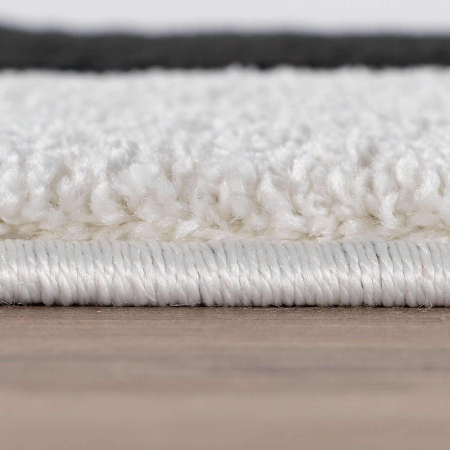 "Close-up of a white textured rug on a wooden floor"