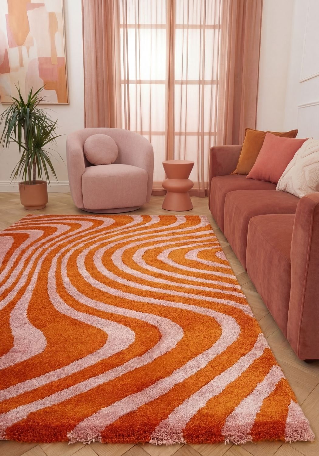 Living room with a wavy orange and pink rug, pink armchair, and sofa.