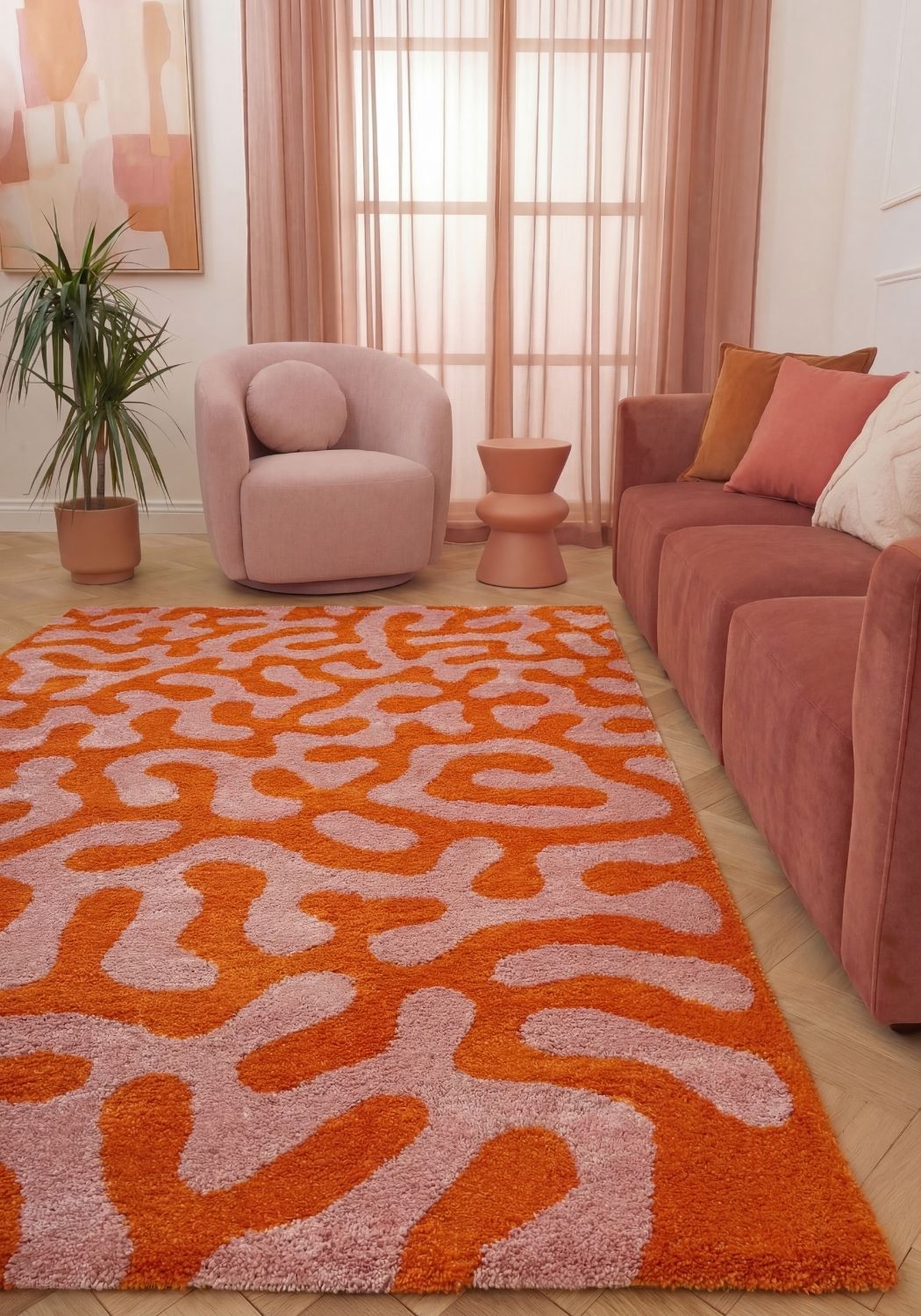 Living room with a coral-patterned orange rug, pink armchair, and sofa.