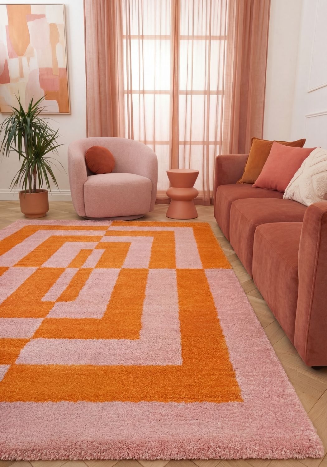 Living room with a geometric patterned rug, pink chair, and sofa.