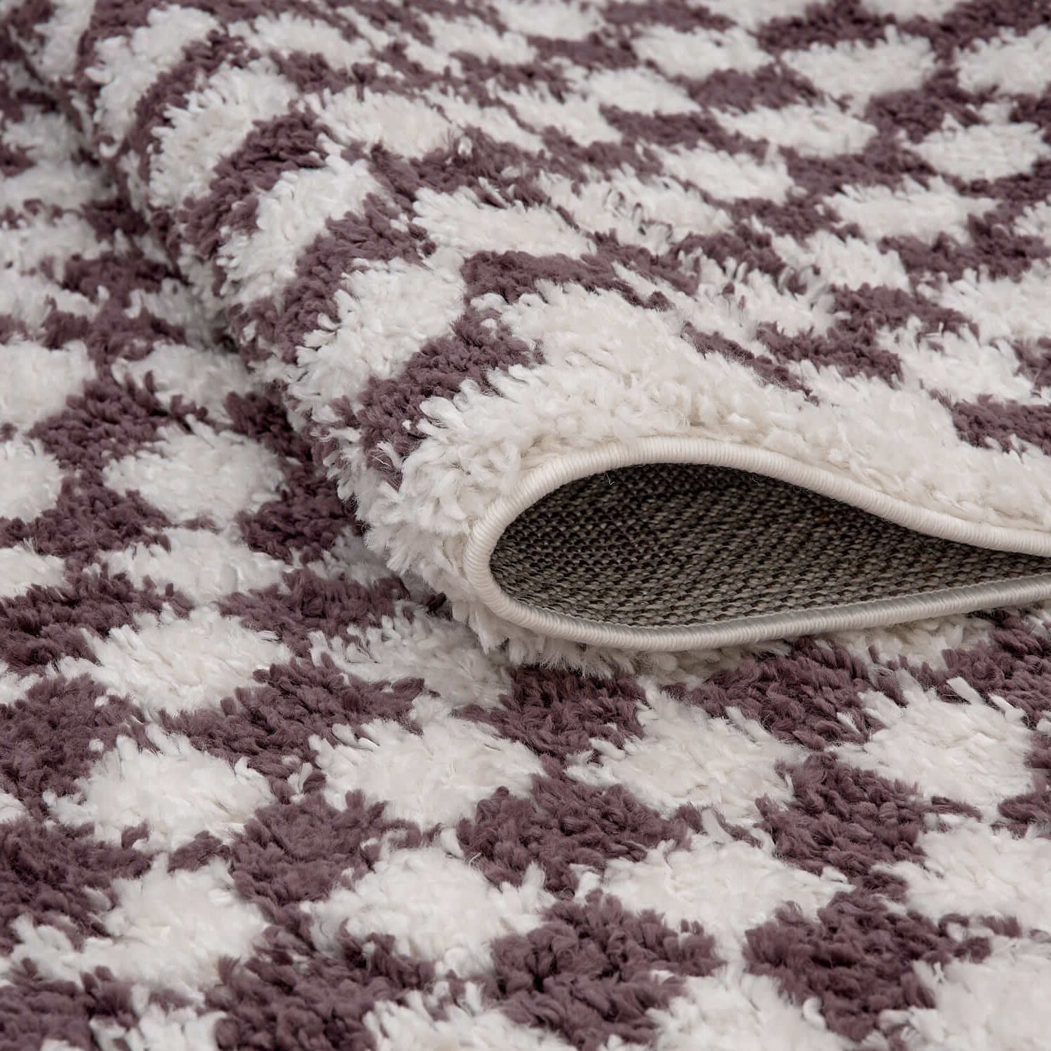 Close-up of a textured purple and white rug with a textured mat on top.