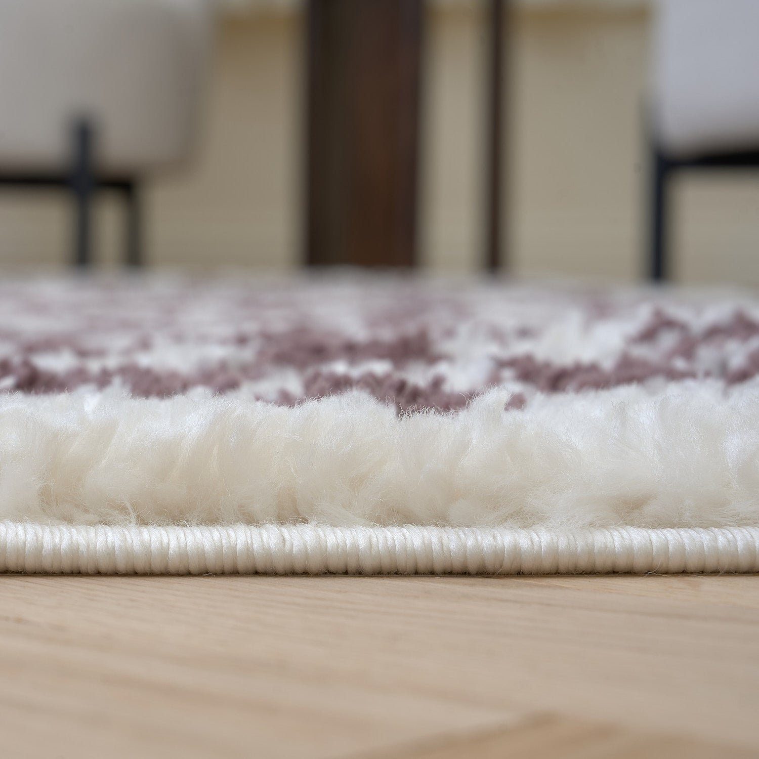 Close-up of a textured rug on a wooden floor with a blurred background