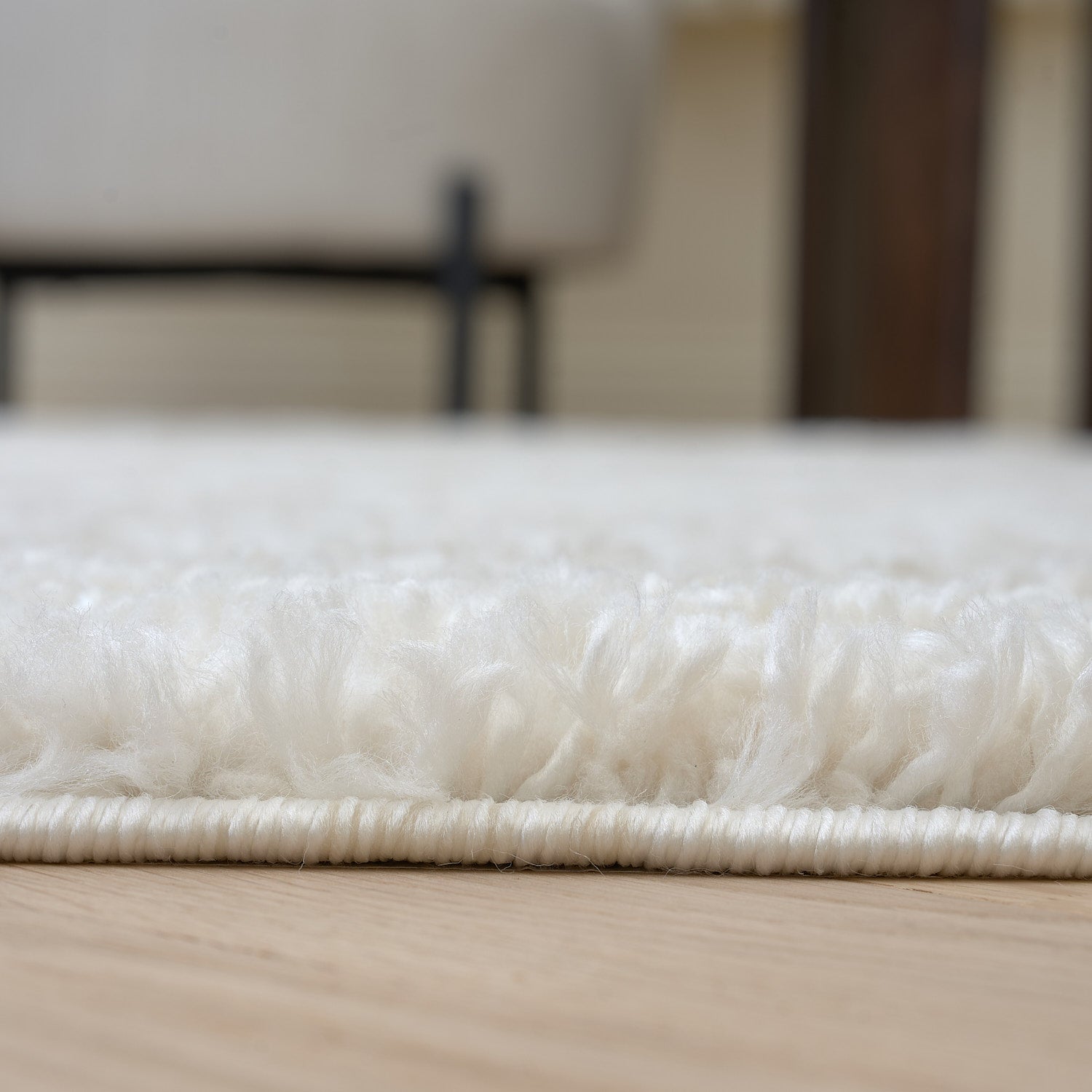 Close-up of a white rug on a wooden floor with a blurred background