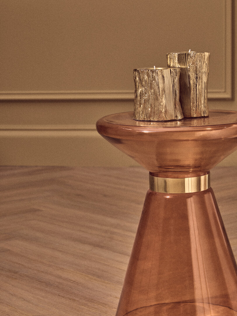 orange glass side table with two decorative candles on a neutral background