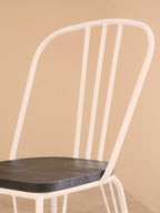 White metal chair with a dark wooden seat against a beige background