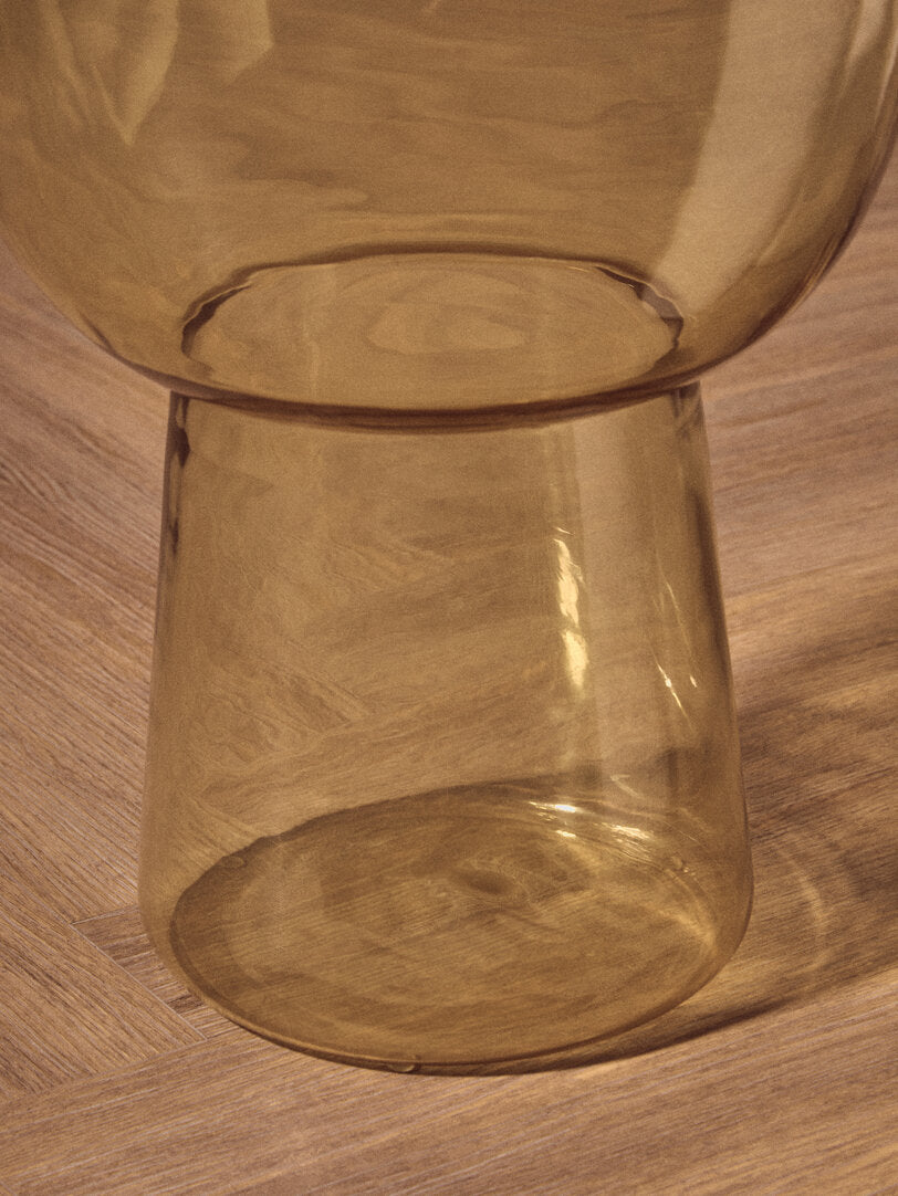 Amber glass side table on wooden floor
