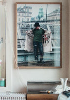 Framed photograph of a person holding a coat on a city street, hanging on a wall.