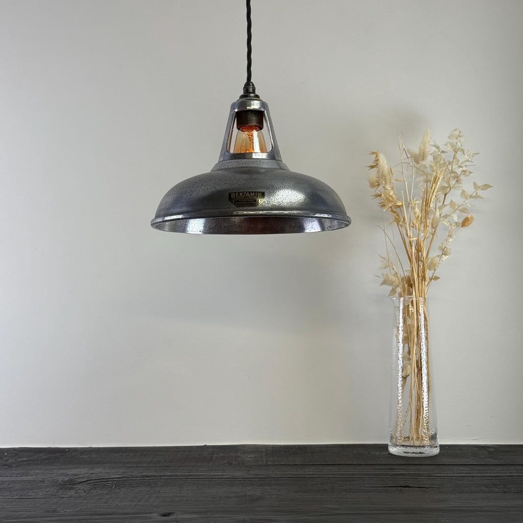 Vintage-style pendant light hanging above a wooden surface with a vase of dried plants.