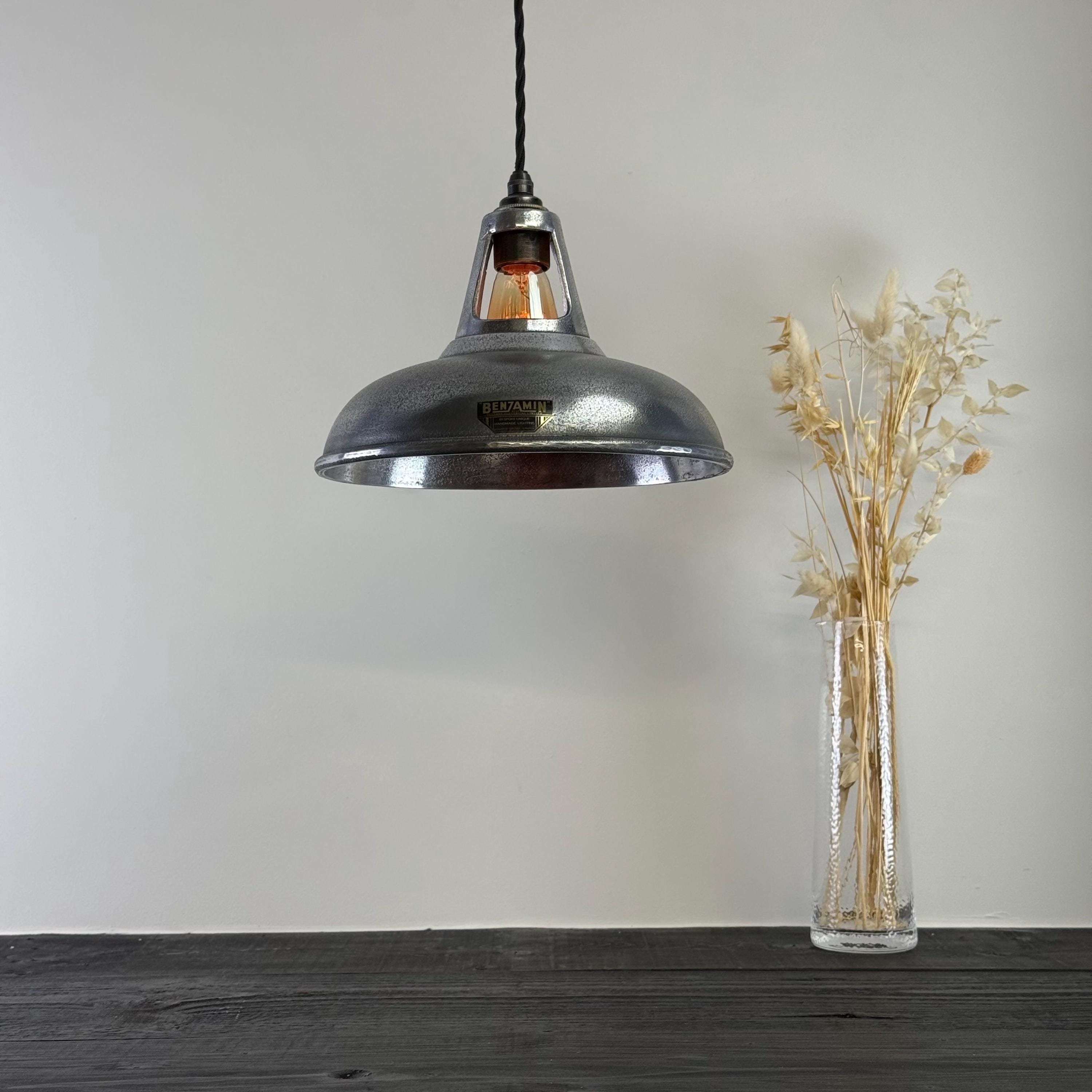 Vintage-style pendant light hanging above a wooden surface with a vase of dried plants.
