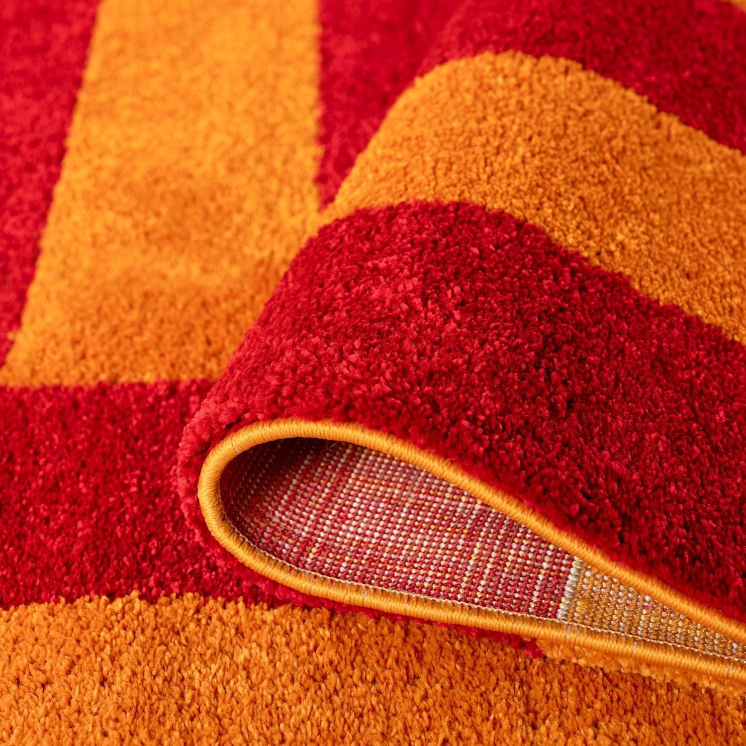 Close-up of a red and orange striped rug with a textured border.