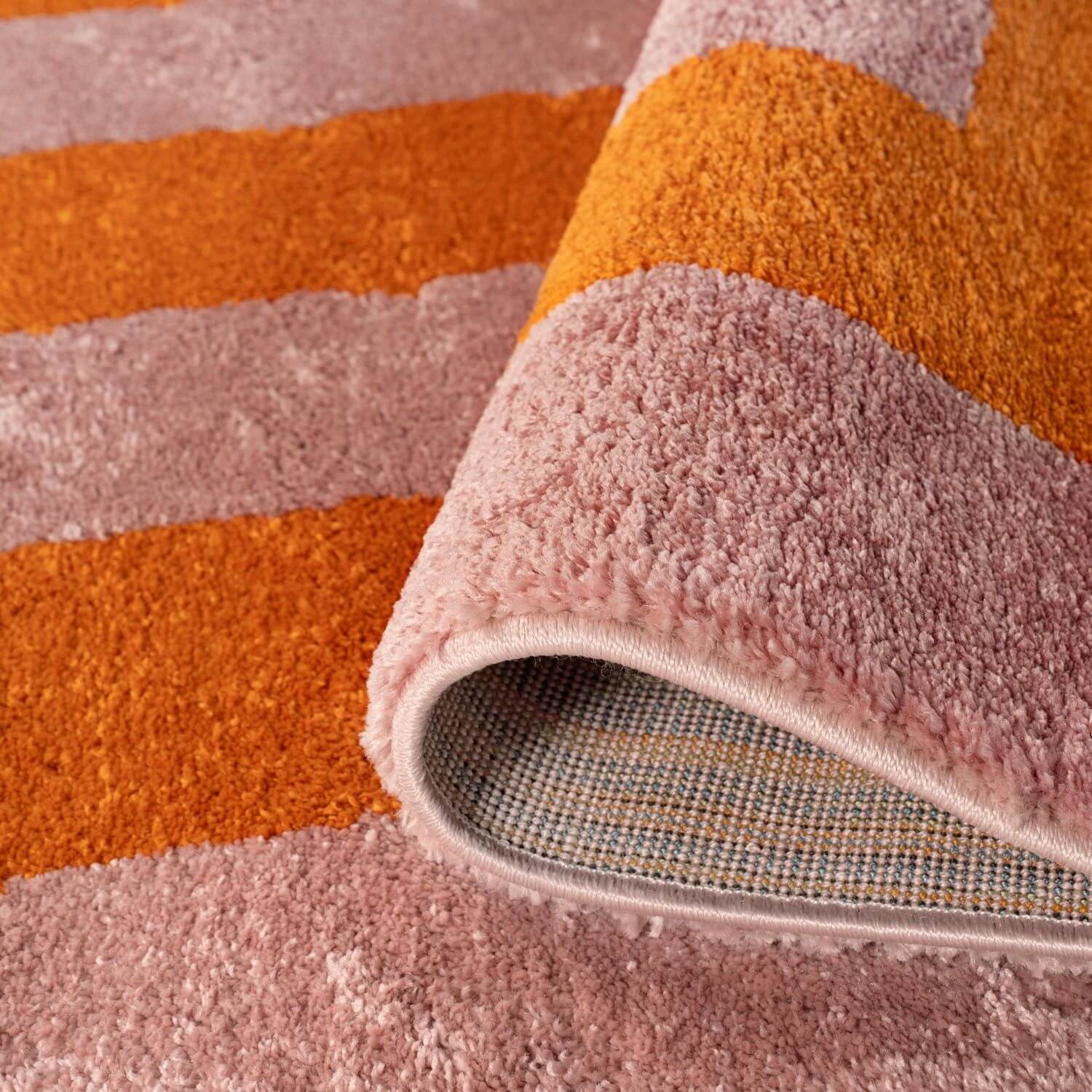 Close-up of a textured rug with orange and pink stripes