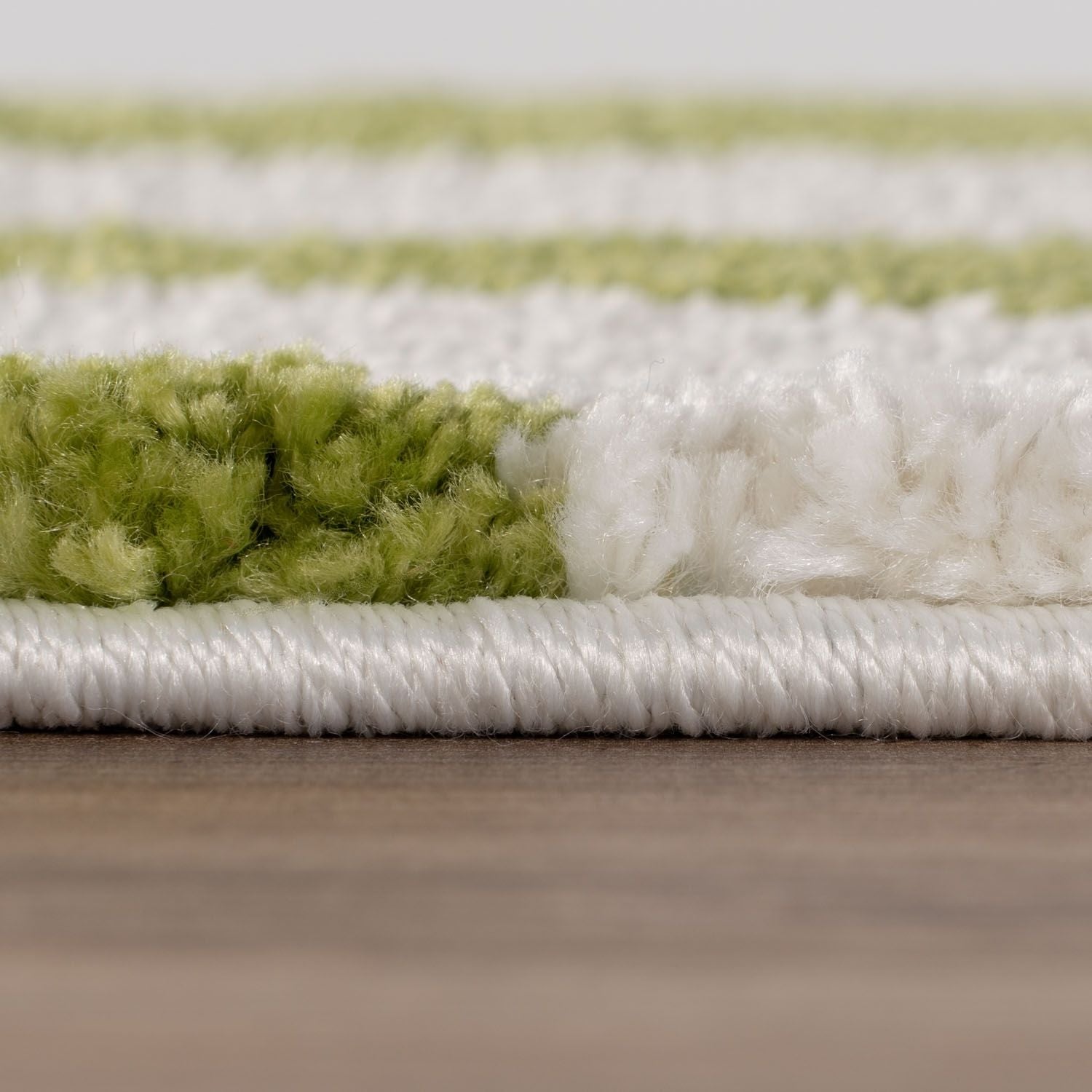 Close-up of a green and white striped rug on a wooden floor.