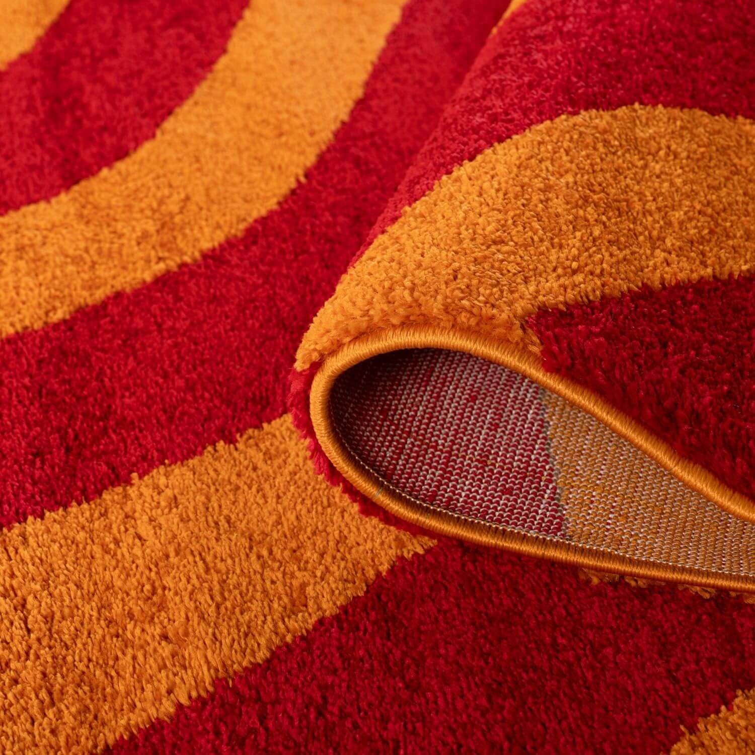 Close-up of a red and orange striped rug with a textured border.