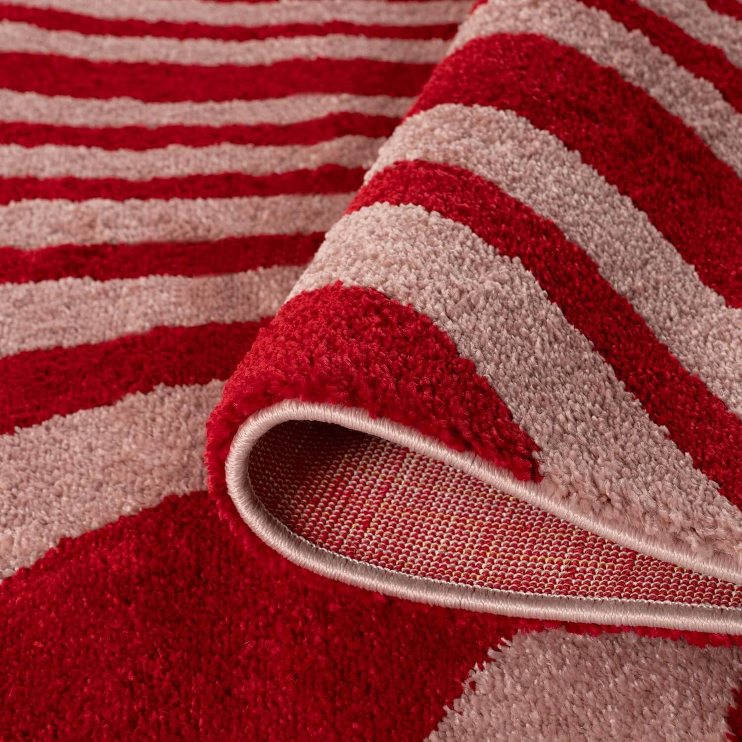 Close-up of a red and pink striped rug with a textured surface.