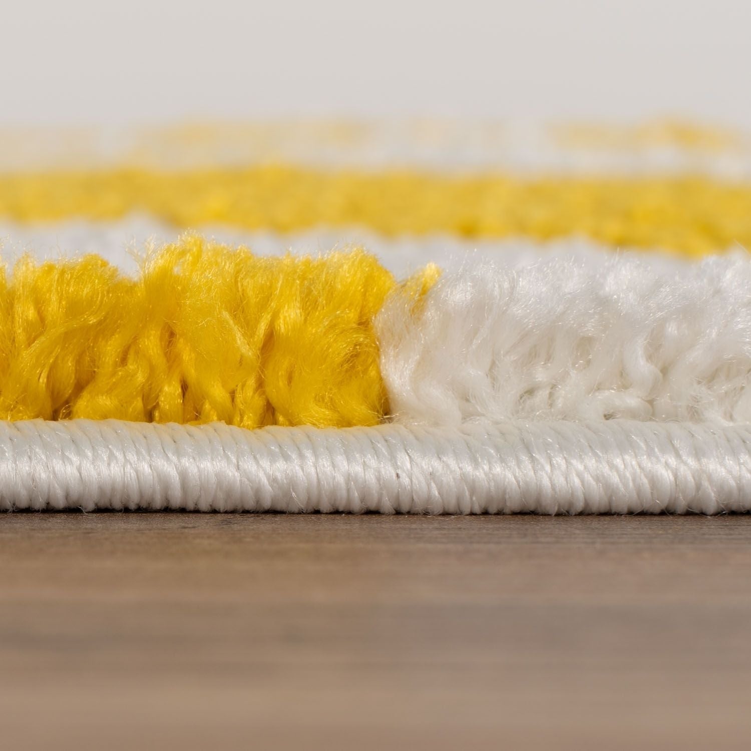 Close-up of a yellow and white rug on a wooden surface.