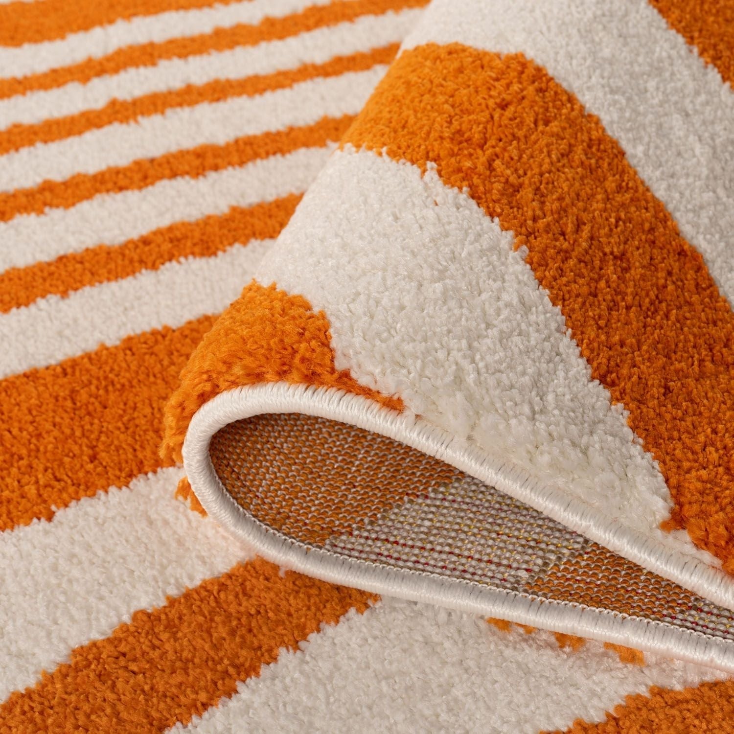 Close-up of an orange and white striped rug with a textured surface.