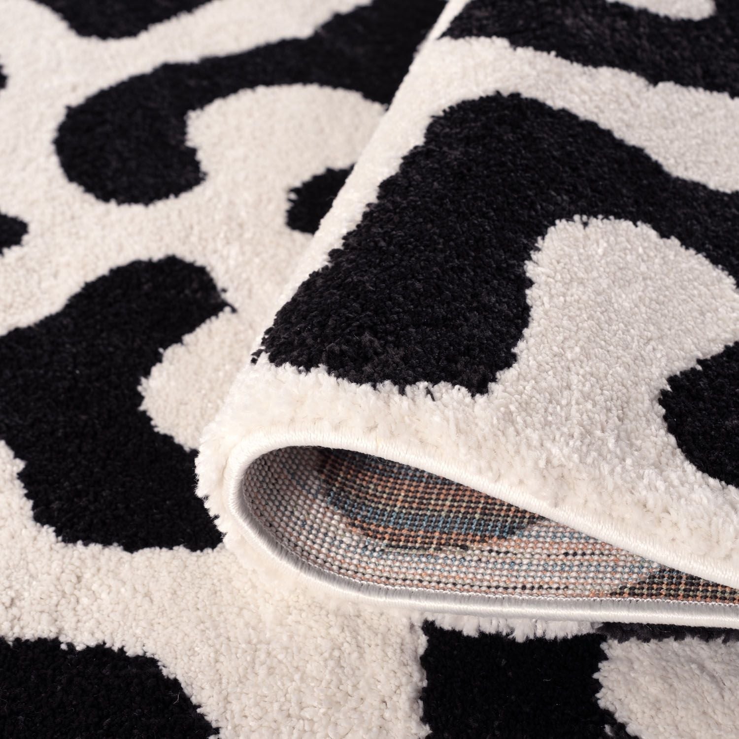 Close-up of a black and white patterned rug with a slippers on top.