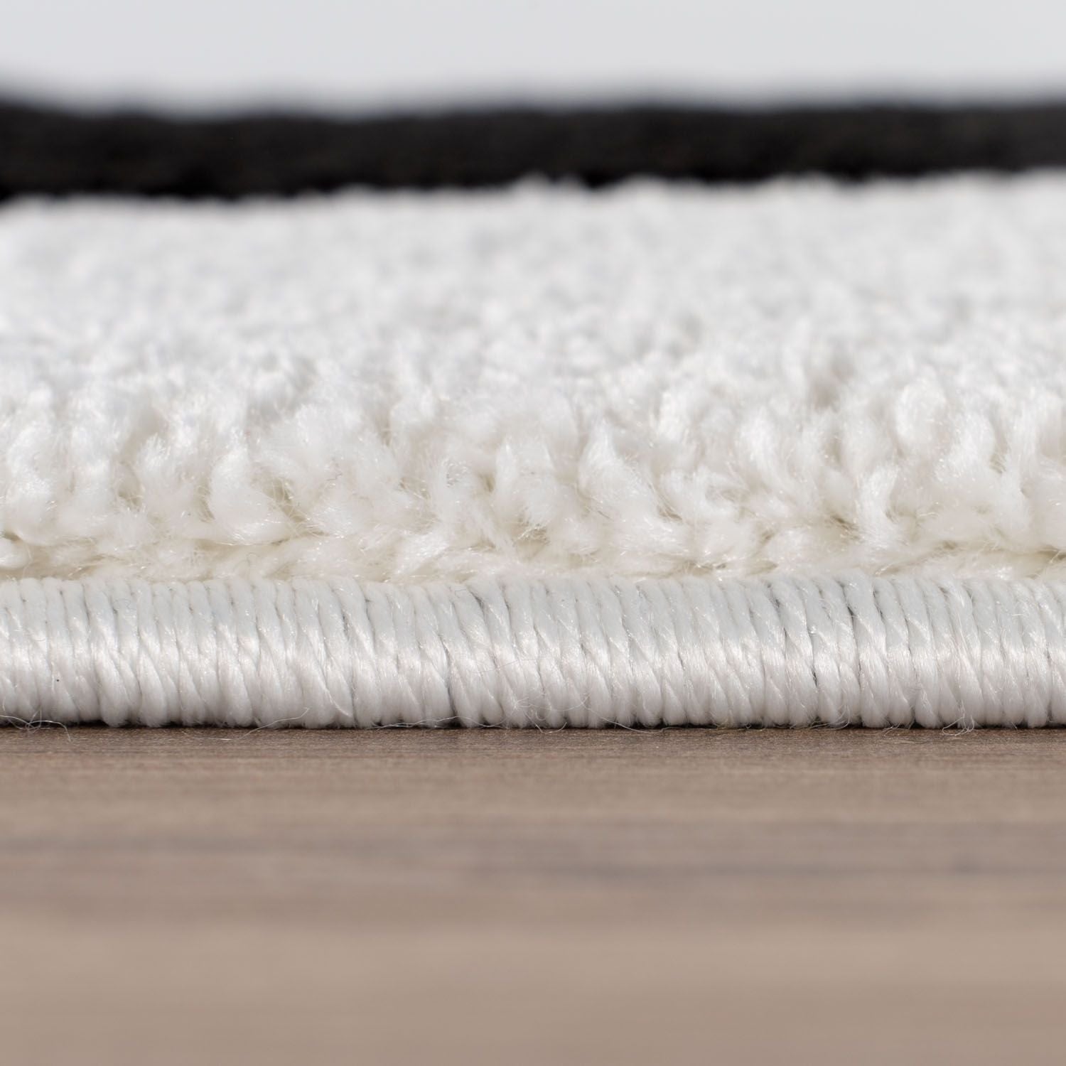 Close-up of a white rug with a textured surface on a wooden floor.