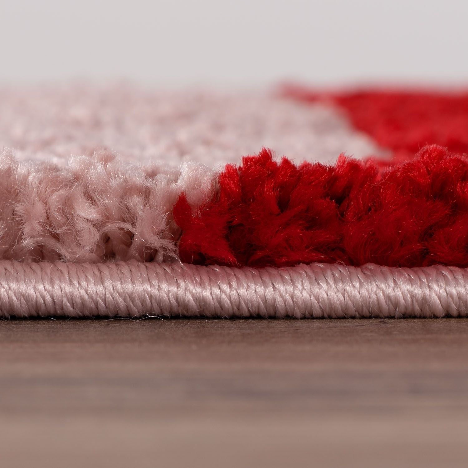 Close-up of a red and pink textured rug on a wooden surface