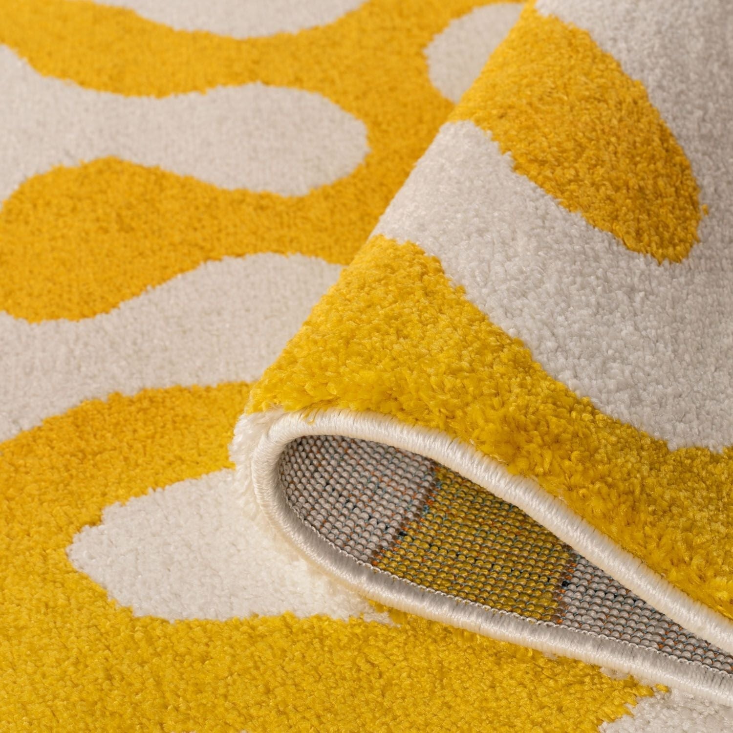 Close-up of a yellow and white patterned rug with a shoe on it.
