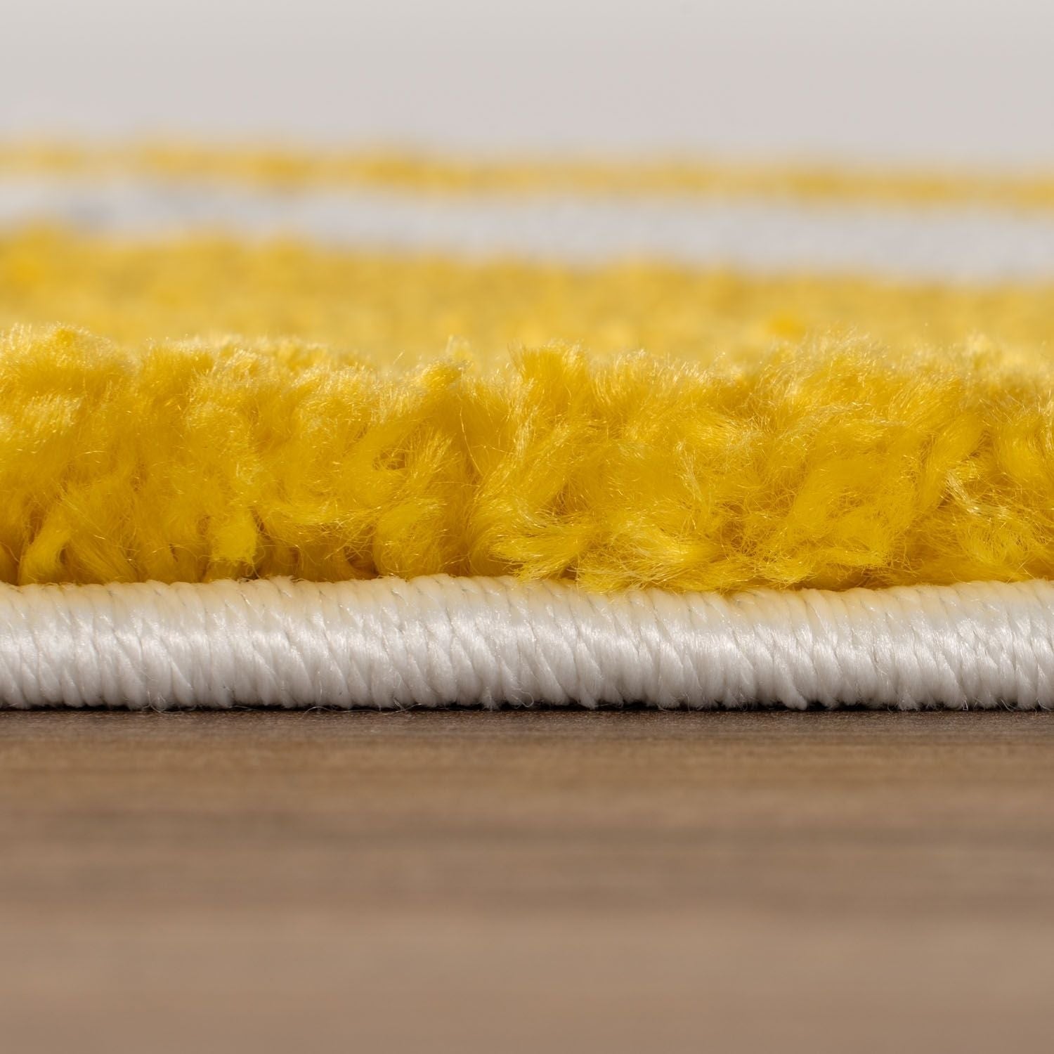 Close-up of a yellow and white carpet on a wooden floor.