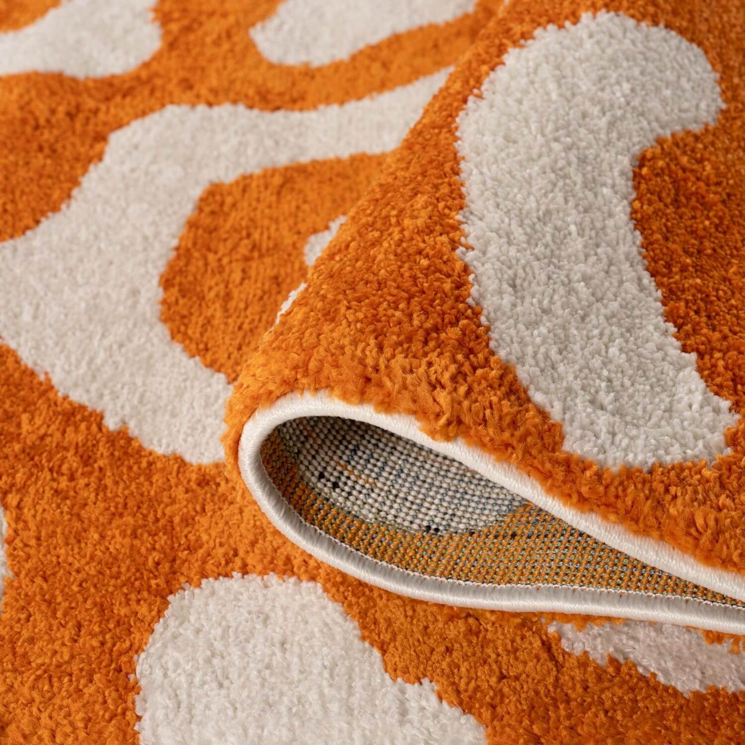 Close-up of an orange and white patterned rug with a textured border.