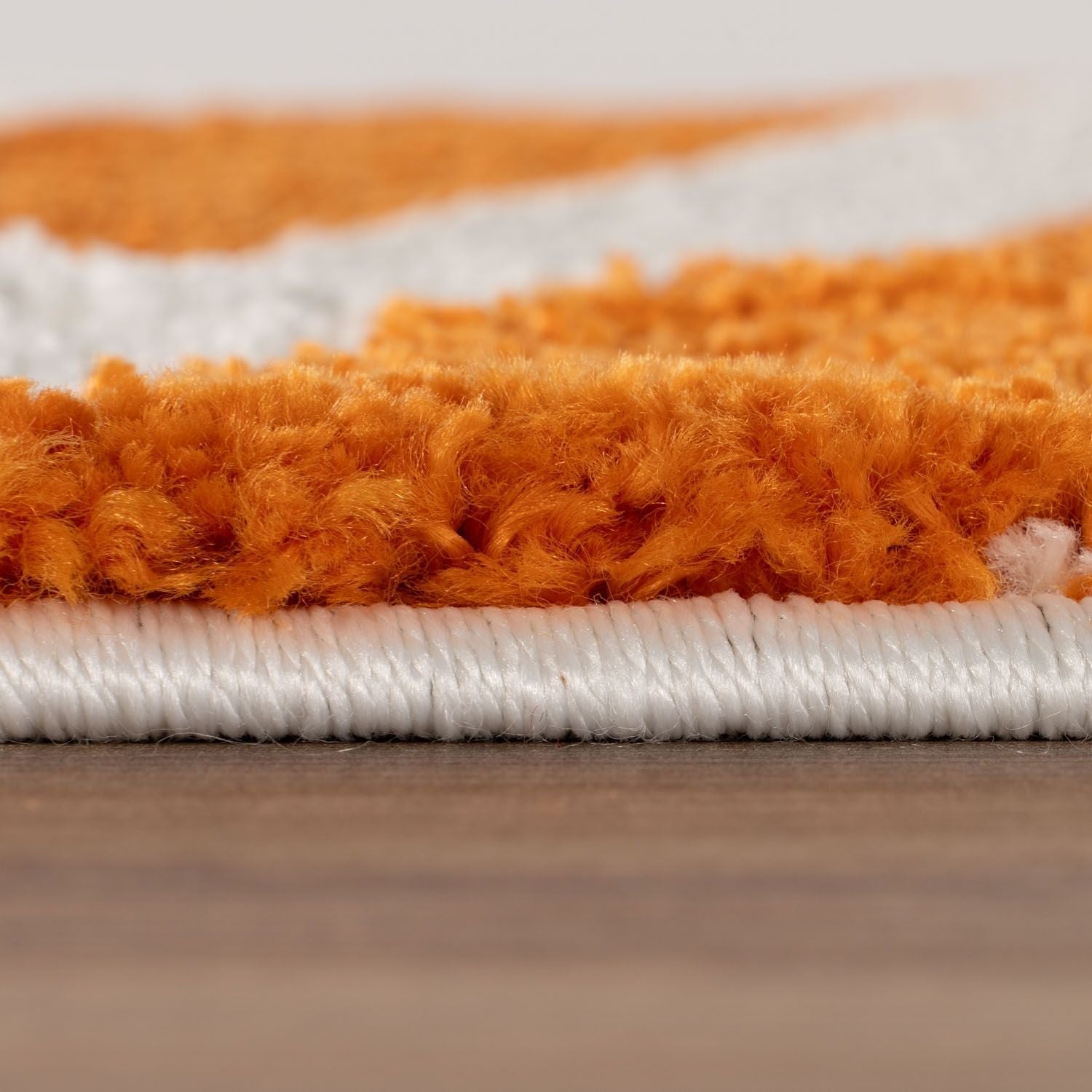Close-up of an orange and white striped rug on a wooden floor.