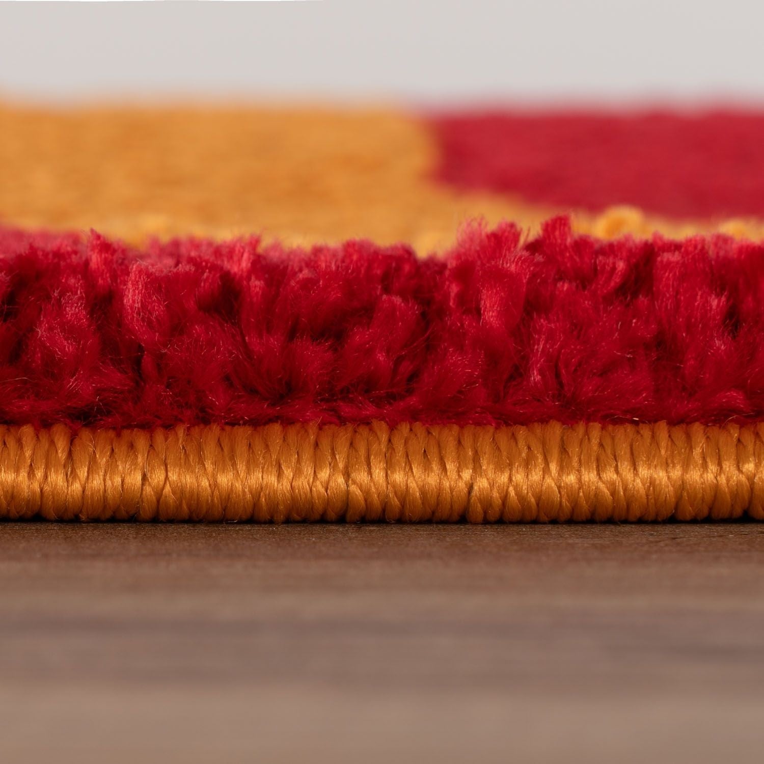 Close-up of red and orange rug strips on a neutral background