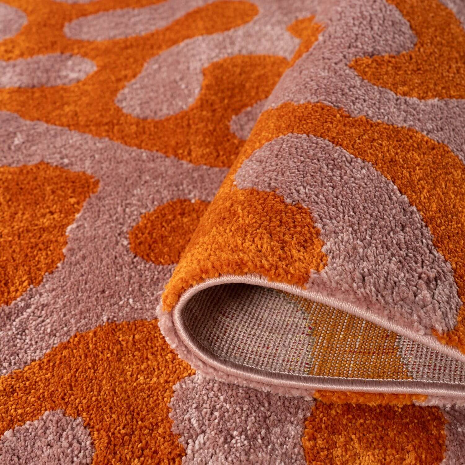 Close-up of a textured orange and pink patterned rug.
