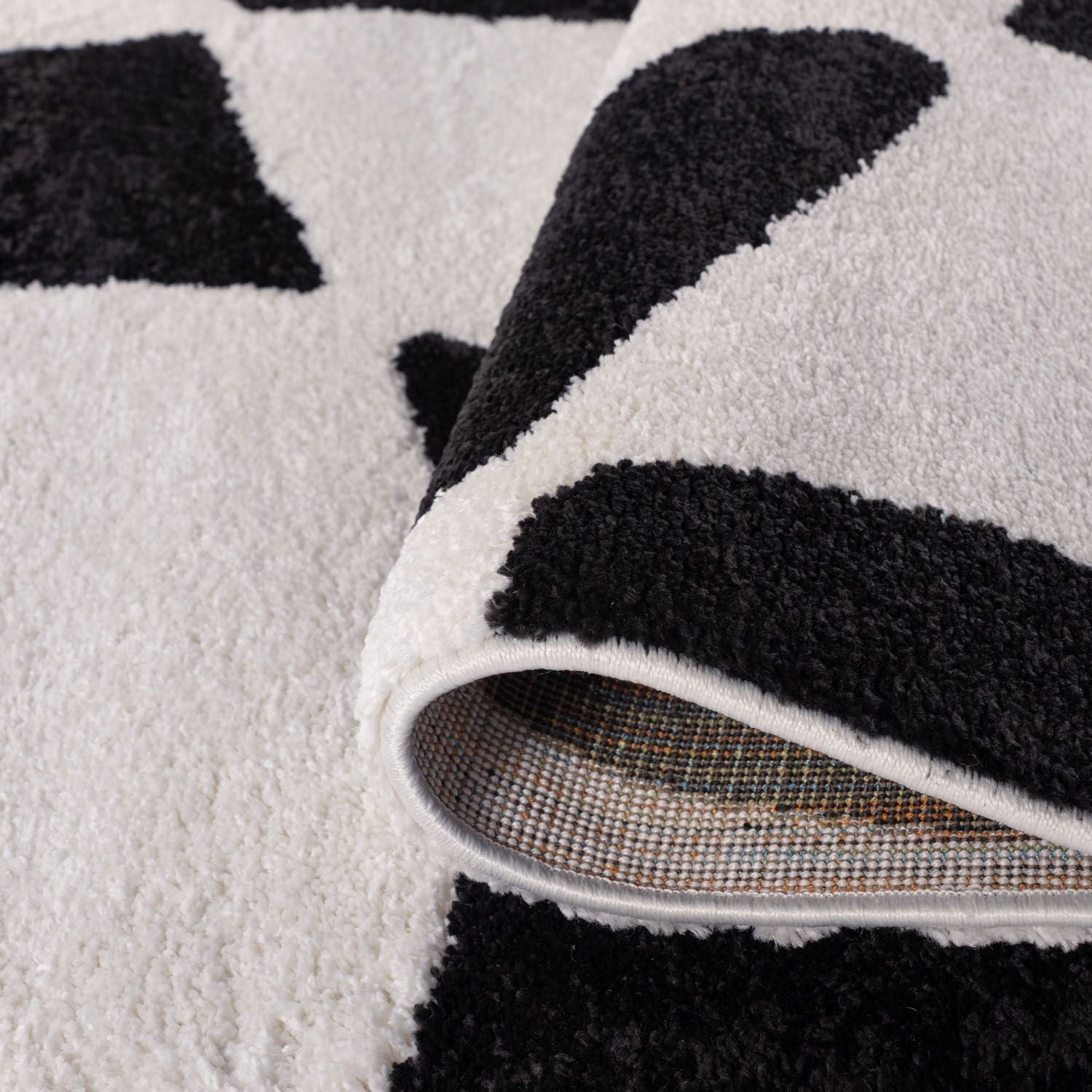 Close-up of a black and white patterned rug with a visible backing.