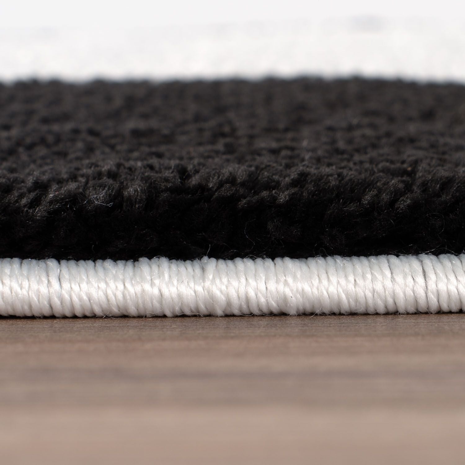 Close-up of black and white textured rug on a wooden surface