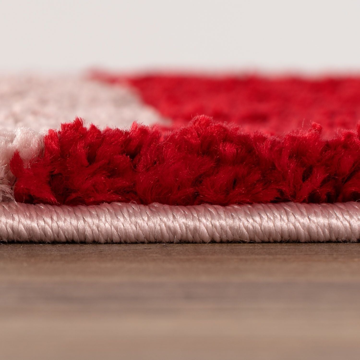 Close-up of a red and pink rug on a wooden floor.