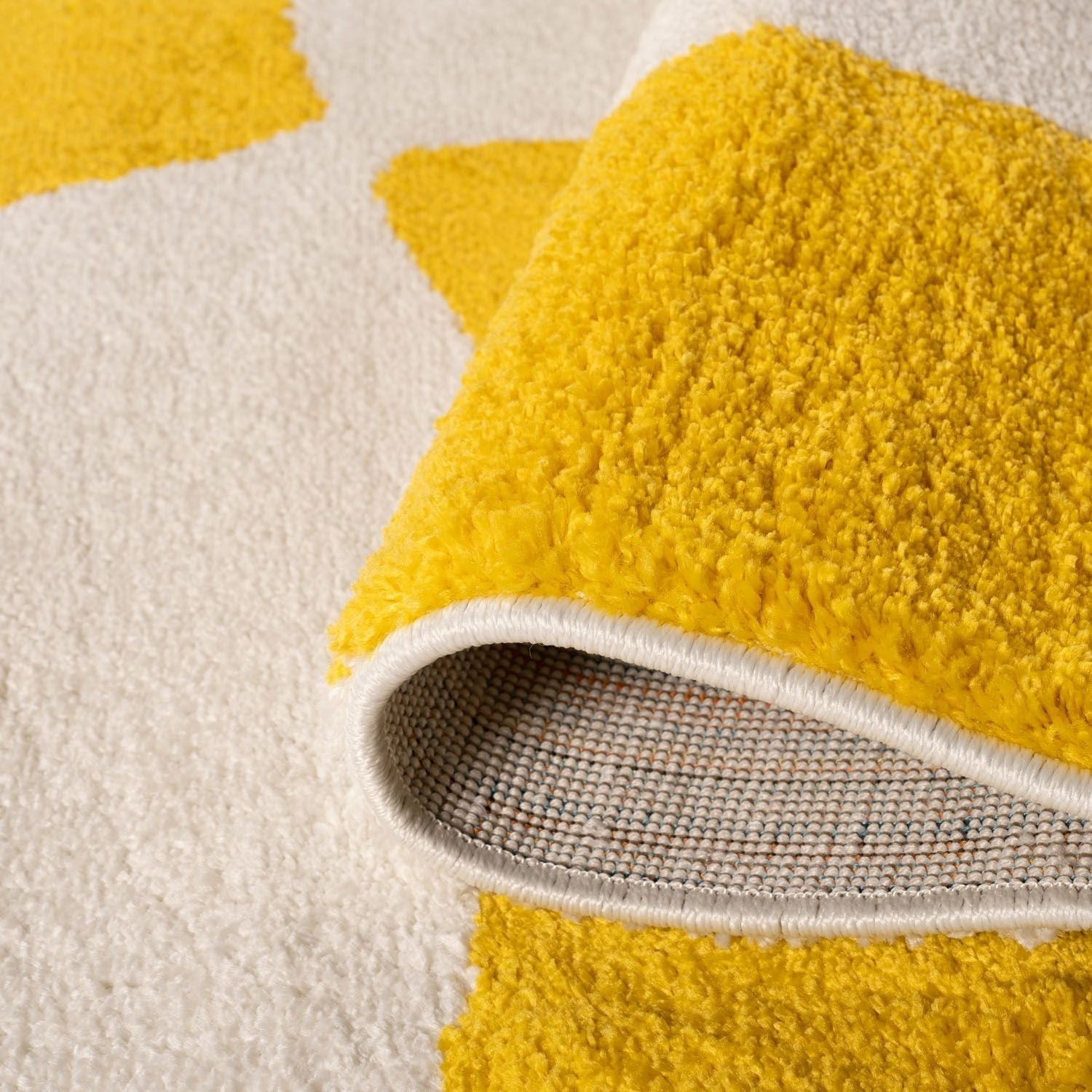 Close-up of a yellow textured rug corner with a backing