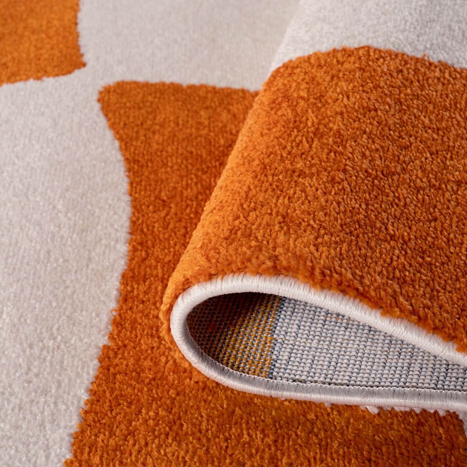 Close-up of an orange and white textured rug with a neutral backing
