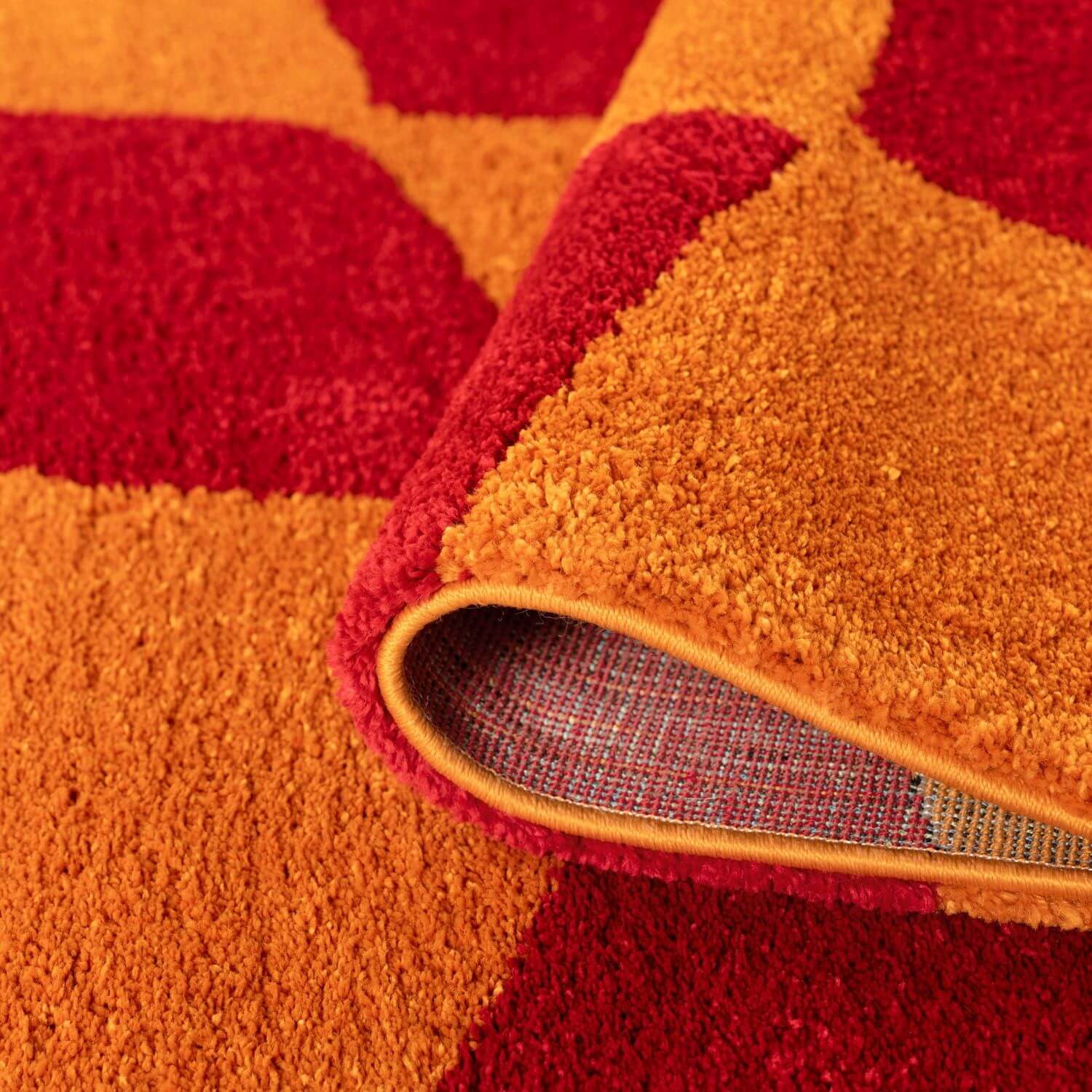 Close-up of a red and orange textured rug with a visible border.
