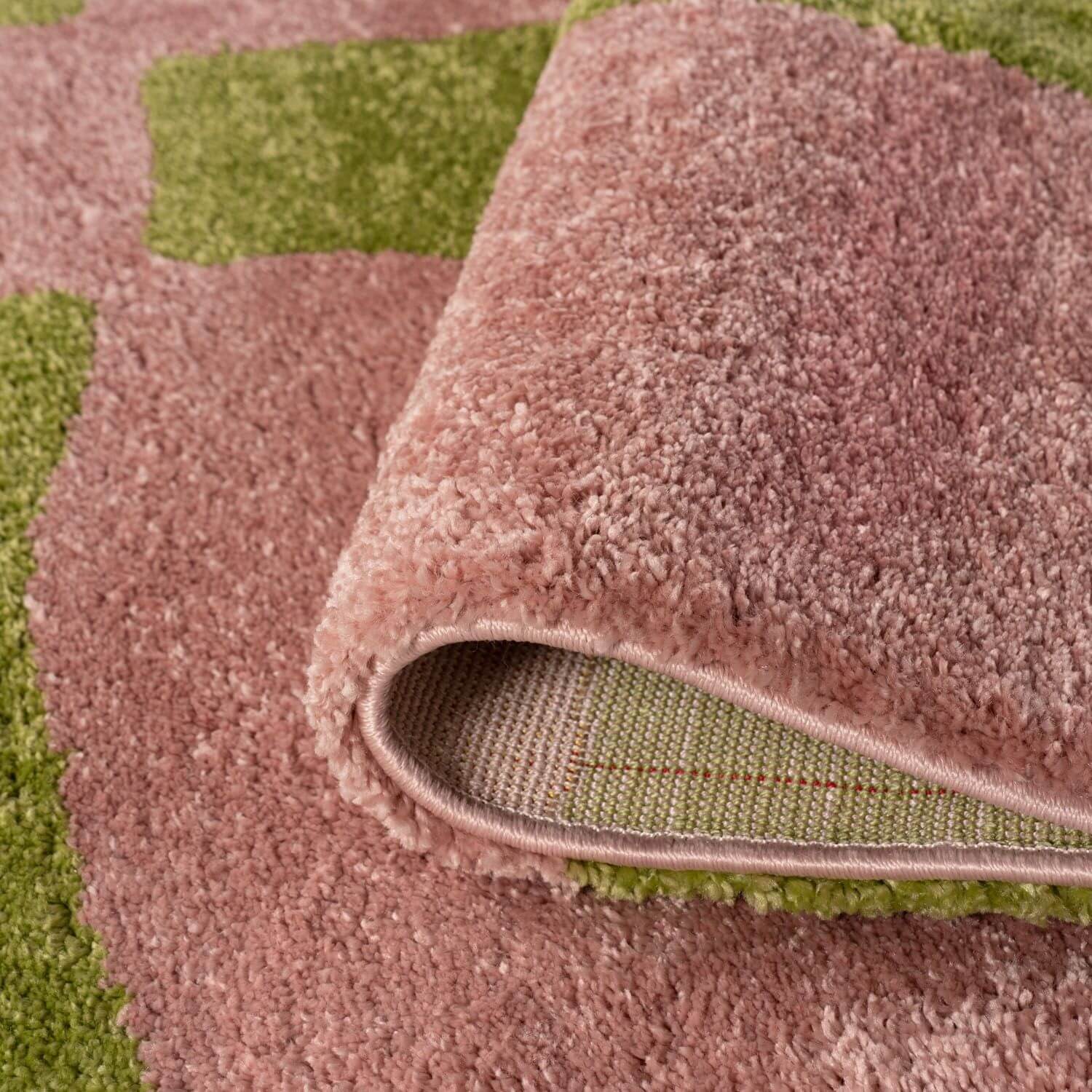 Close-up of a pink textured rug with a green checkered pattern.