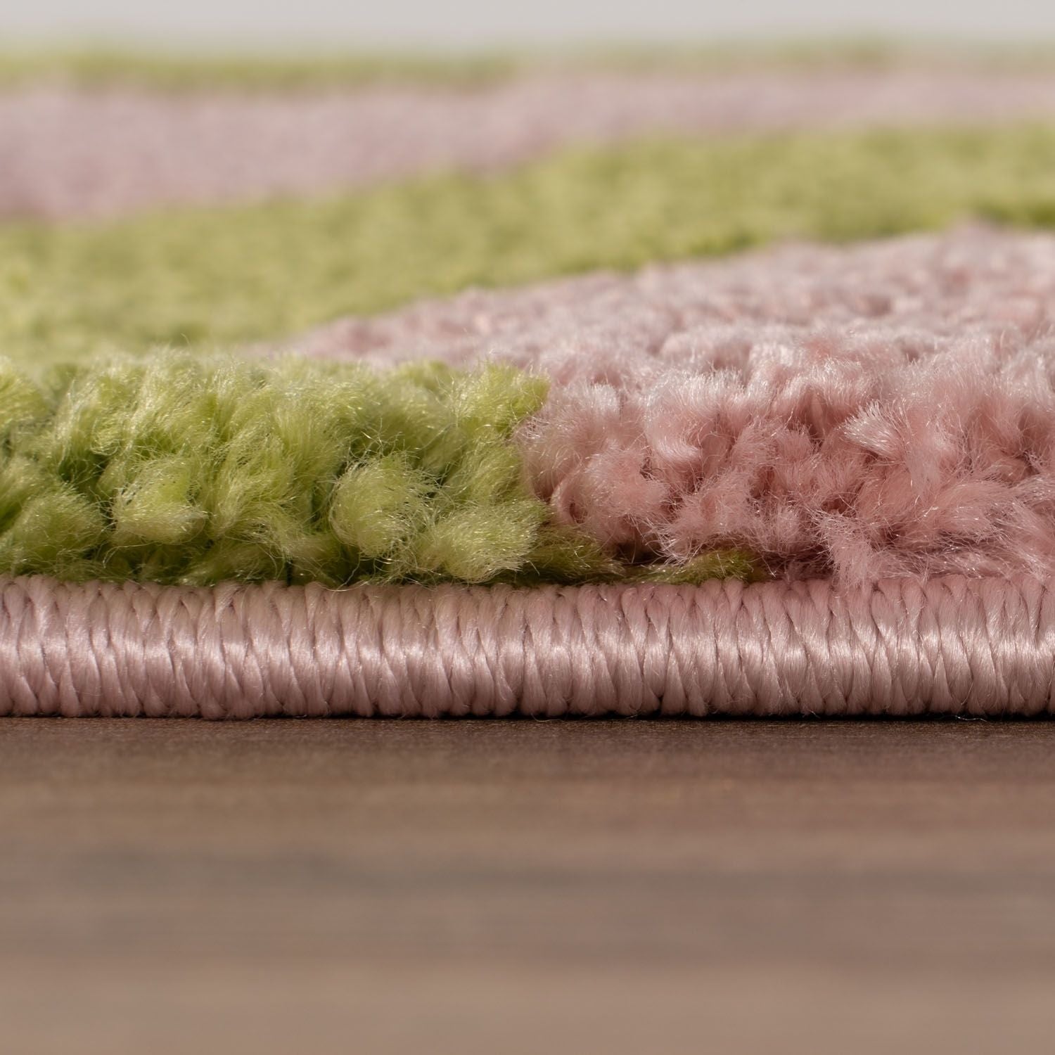 Close-up of a multicolored textured rug with green, pink hues.